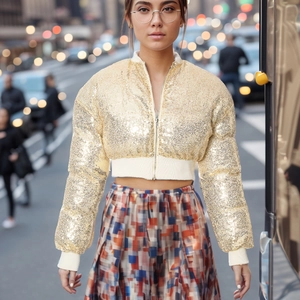 Detail of gold sequin cropped jacket showing zipper closure and elastic ribbed cuffs