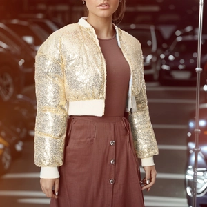 Detail shot of golden sequin bomber jacket with white ribbed cuffs and zipper closure
