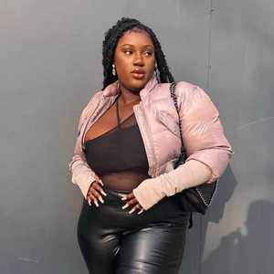 Close-up of a glossy mauve puffer jacket paired with a black mesh top and leather pants