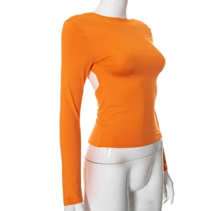 Dettaglio del top attillato arancione a maniche lunghe con design cut-out su manichino