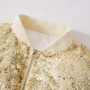 Detail of gold sequin jacket featuring ribbed collar and metallic zipper texture