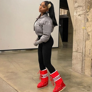 Street style shot of a grey slim fit puffer jacket and vibrant red winter snow boots