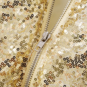 Detailed macro view of gold sequins and metal zipper on the sequined cropped jacket