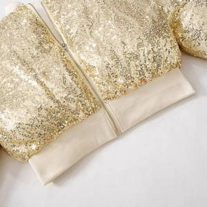 Close-up of golden sequin jacket featuring metallic zipper and ribbed knit hem details