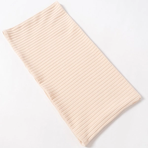 Detailed close-up of light peach ribbed knit fabric showing elastic vertical texture