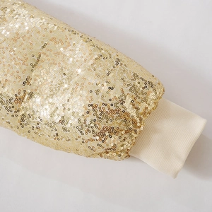 Detail of golden sequin fabric with off-white ribbed knitted cuffs on a slim jacket