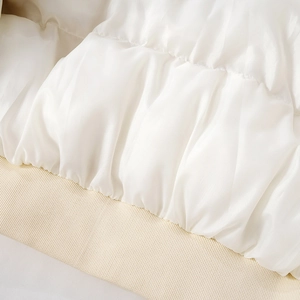 Detailed close-up of white sequin quilted fabric and beige ribbed hem on slim jacket