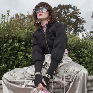 Detail of a black puffer jacket with utility pockets and elastic cuffs in outdoor setting