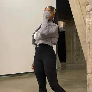Detail of a grey quilted puffer jacket and high-waist black leggings on a female model