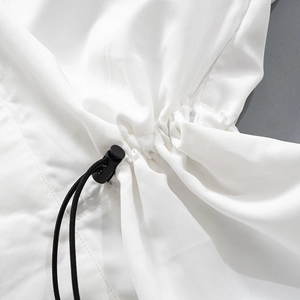 Détail d'un gilet blanc avec cordon de serrage noir réglable et embouts en plastique