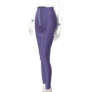 Dettaglio di leggings compressivi viola a vita alta con chiusura a gancio frontale