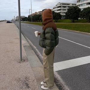 Detail shot of a dark green cropped puffer jacket paired with khaki cargo pants in the street