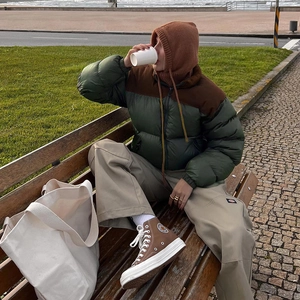 Detail shot of padded cropped puffer jacket styled with khaki cargo pants and tote bag
