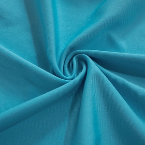 Detailed close-up of teal ribbed knit fabric texture with spiral drape pattern