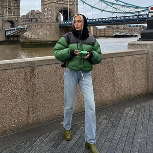 Women's green padded puffer jacket with straight blue jeans and boots at London Bridge