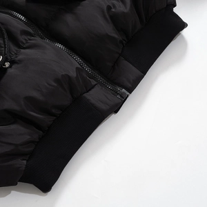 Detail of black quilted puffer jacket featuring smooth metal zipper and ribbed knit hem