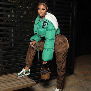 Detailed view of women's green puffer jacket with F embroidery and white fleece hood lining