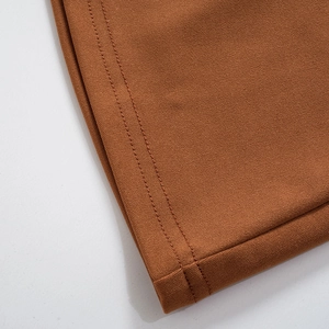 Detalle de los pantalones marrón caramelo con costuras de doble aguja y textura de la tela