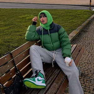 Street style shot of a green puffer jacket paired with a knit face mask and grey joggers