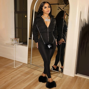Detail of a chic black quilted puffer vest and slim jumpsuit with metal zipper