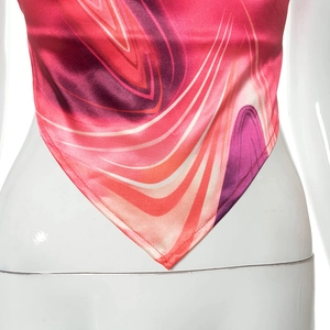 Detail of satin halter top featuring abstract colorful patterns and pointed hemline