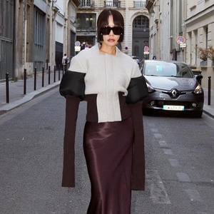 Detailed view of color-block jacket with bubble sleeves and smooth red satin skirt