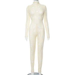 Détail d'une combinaison en maille beige avec col montant et motifs à trous déchirés