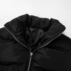 Detail of high stand collar and silver metal zipper on the black quilted padded jumpsuit