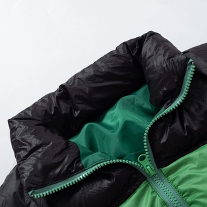 Detail of high neck collar with green resin zipper and shiny black quilted fabric