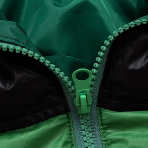 Detail of a green and black quilted jacket featuring a durable matching plastic zipper closure