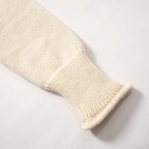 Détail des poignets en maille côtelée sur ce haut en tricot crème dos nu élégant