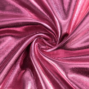 Detailed macro view of vibrant hot pink metallic coated fabric with stylish swirl draping