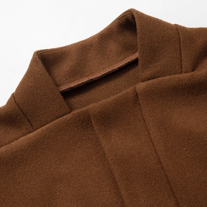 Detailed close-up of brown wool jacket collar showing precision stitching and fabric texture