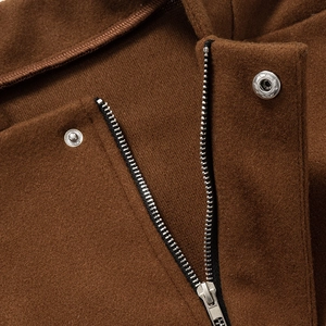 Close-up of the silver metal zipper and snap button on a brown wool blend jacket