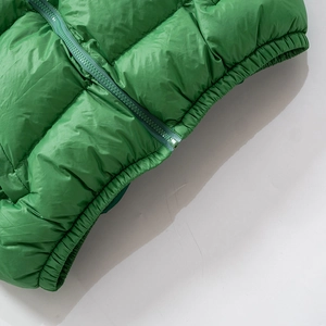 Detail view of bright green puffer jacket showing zipper, hem, and quilted fabric texture