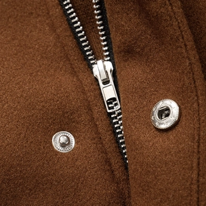 Close-up of silver metal zipper and snap buttons on brown textured winter jacket