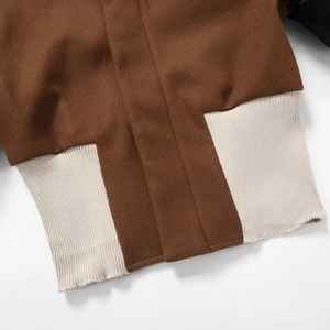 Detail of contrast rib-knit hem on brown and beige slim-fit baseball style jacket
