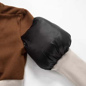 Detail of color-block jacket showing wool body, glossy black sleeves and ribbed cuffs