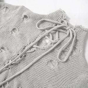 Détail de la combinaison en maille gris clair avec laçage et trous délavés tendance