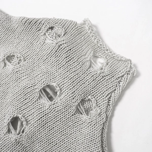 Détail d'une combinaison en tricot gris clair avec texture déchirée et maille épaisse