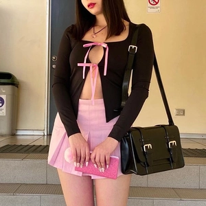 Haut en maille noire avec découpe frontale et détails de nœuds en ruban rose pastel