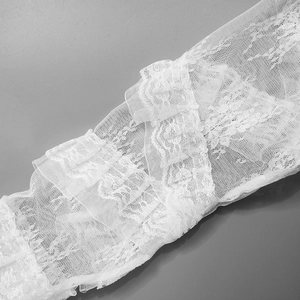Dettaglio macro del tessuto in pizzo bianco con delicati ricami floreali a più strati
