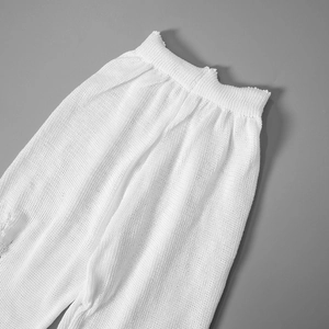 Close-up of white knitted trousers with elastic waistband and fine mesh texture detail