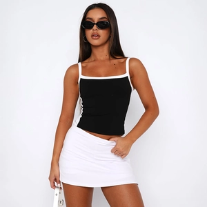 Detail of a black cropped tank top with white piping and a matching white mini skirt