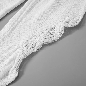 Close-up of delicate white crochet scalloped hem and hollow lace texture on knitted garment
