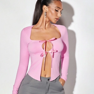 Détail du haut rose à manches longues avec découpe poitrine et nœud en ruban de satin chic