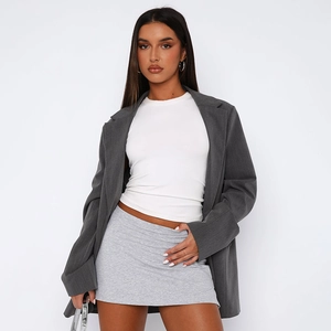 Detail of grey oversized blazer paired with white tank top and mini jersey skirt