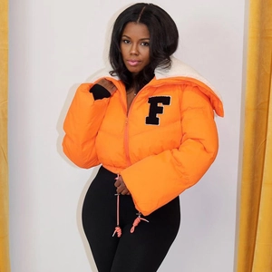 Detail of bright orange puffer jacket featuring black letter F embroidery and white faux fur collar