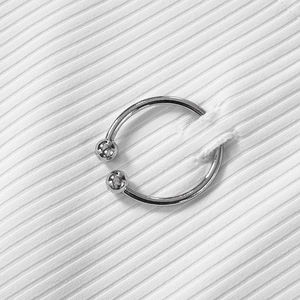 Macro di anello a ferro di cavallo in acciaio lucido su tessuto bianco a coste