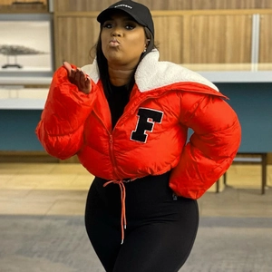 Detail of orange puffer jacket featuring white faux shearling collar and letter F patch